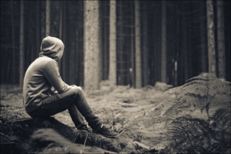 Человек в капюшоне сидит