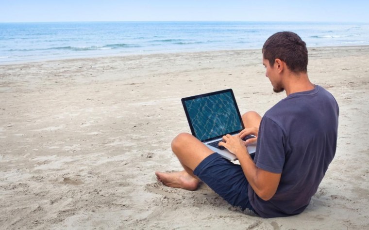 Бизнесмен на пляже с ноутбуком