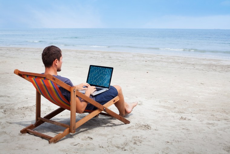 Мужчина на берегу моря с ноутбуком