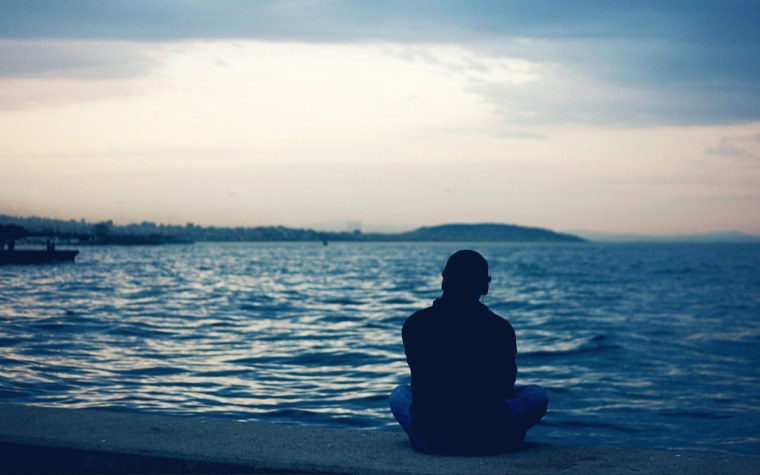 Парень сидит на берегу моря