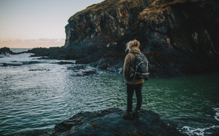 Девушка сидит на скале спиной