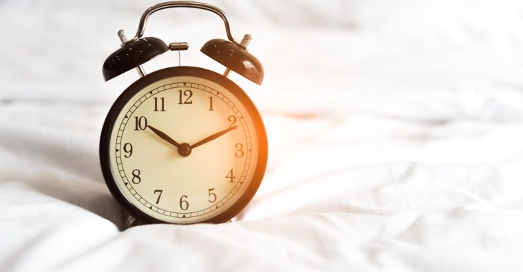 Часы лежат кровати на белом фоне