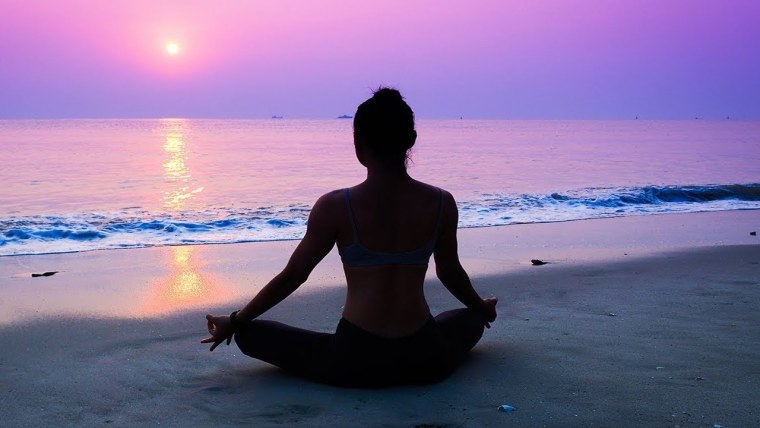 Девушка медитирует на берегу