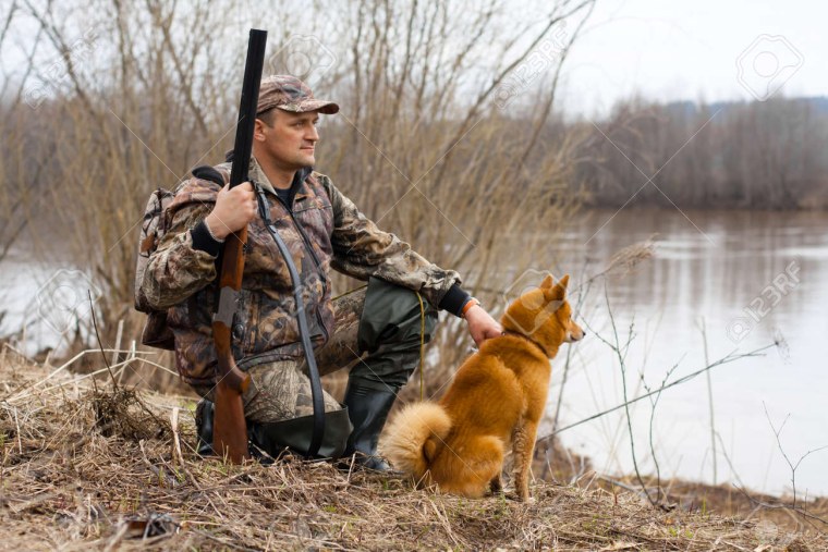 Охотник сидит с ружьем