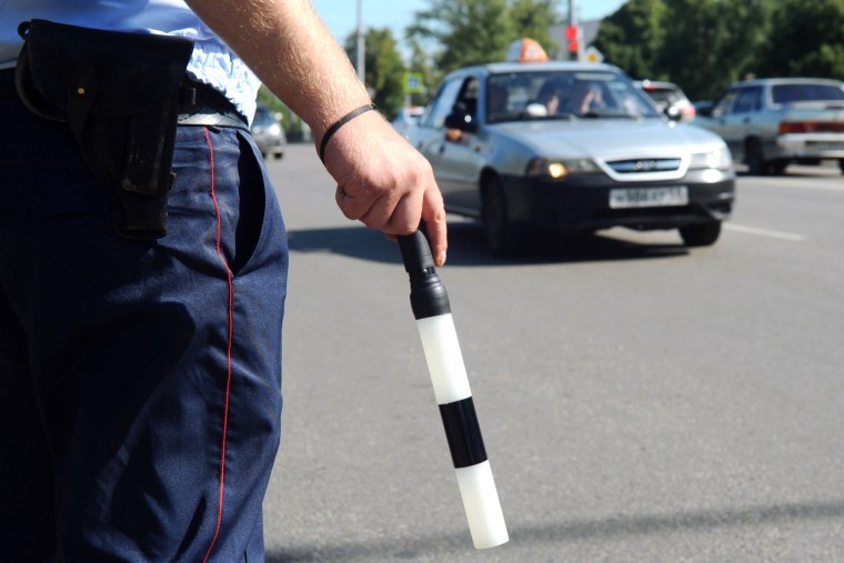 Сотрудник ГИБДД С жезлом за спиной