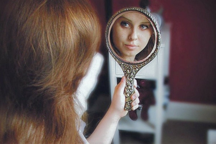 Девушка смотрит в зеркало