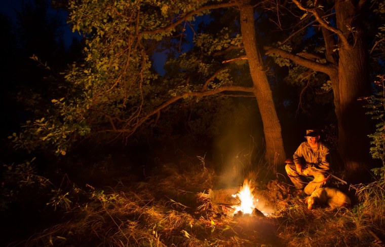 Охотник у костра в лесу