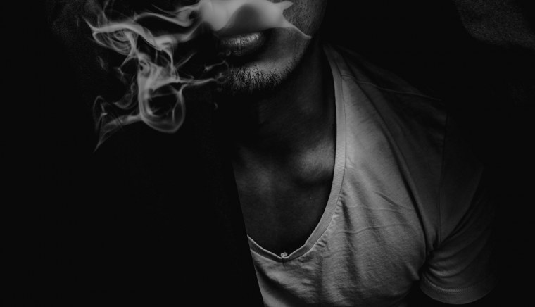 Мужчина с сигаретой в темноте