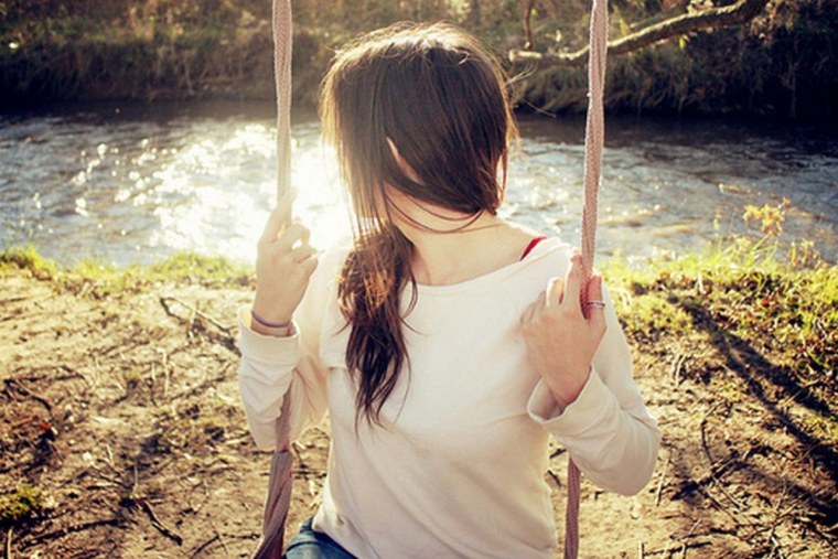 Брюнетка на качелях со спины